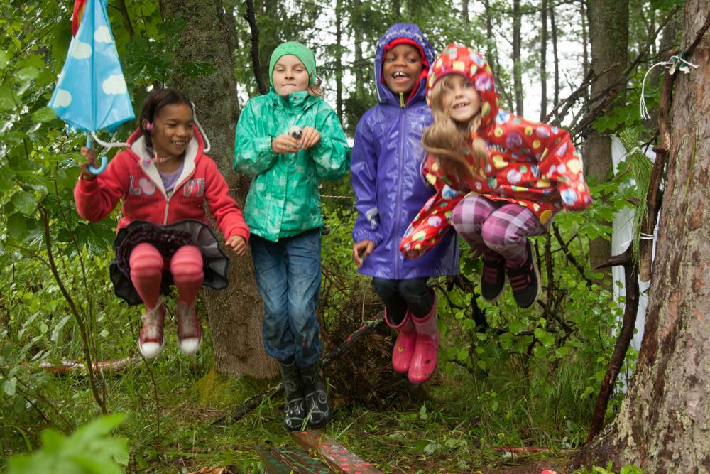 lapset hyppivät metsässä sadetakit päällä